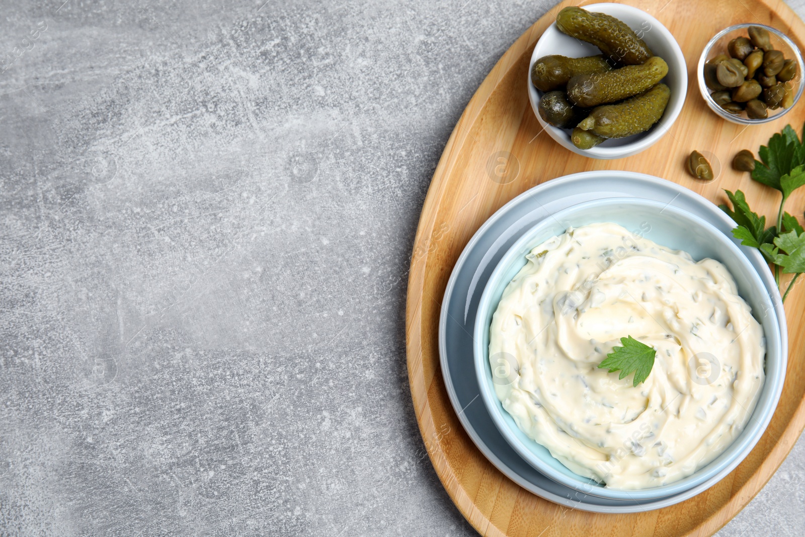 Photo of Tasty tartar sauce and ingredients on grey table, top view. Space for text