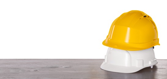 Photo of Hard hats on wooden table against white background. Safety equipment