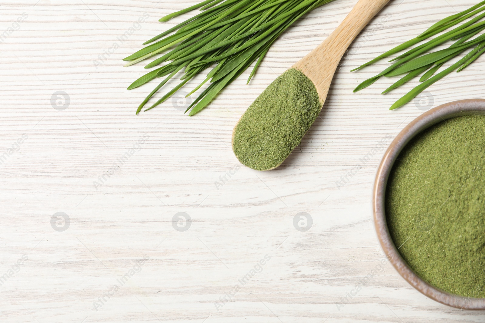 Photo of Wheat grass powder and fresh sprouts on white wooden table, flat lay. Space for text