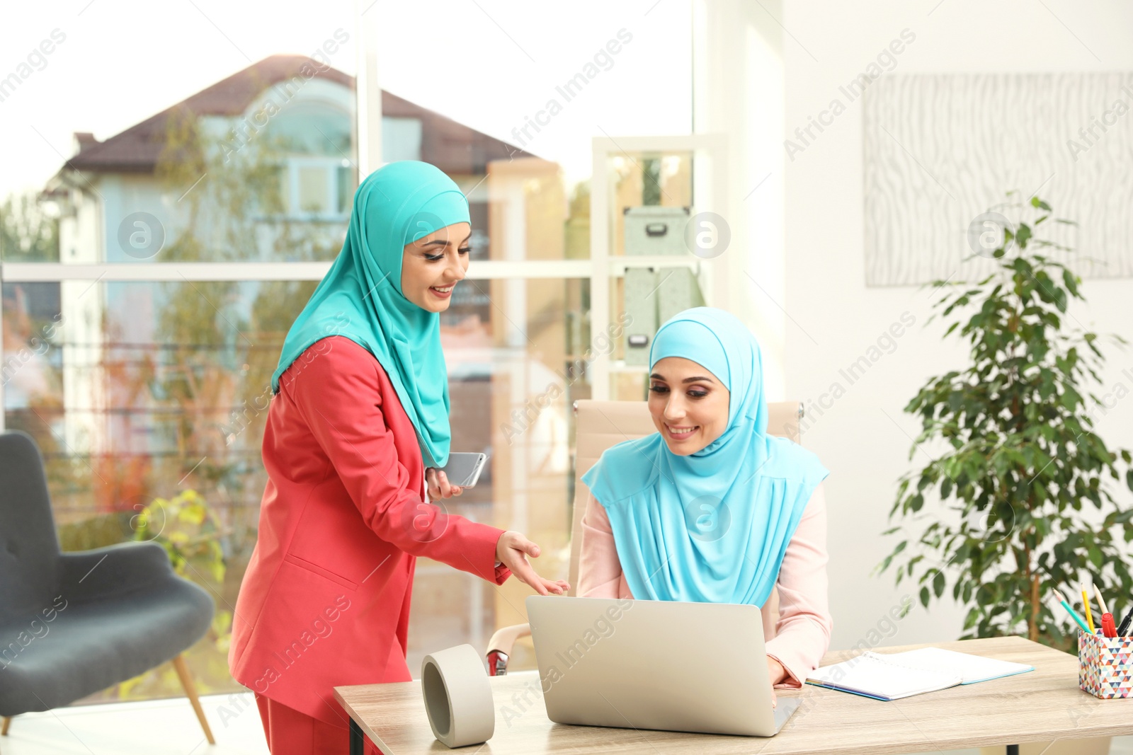 Photo of Modern Muslim women working in light office