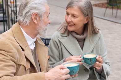 Photo of Portrait of affectionate senior couple drinking coffee in outdoor cafe