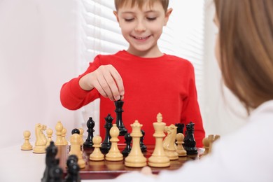 Photo of Cute children playing chess at table indoors, closeup