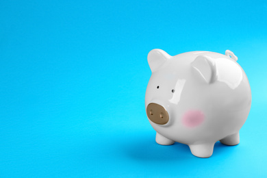 White piggy bank on blue background. Space for text