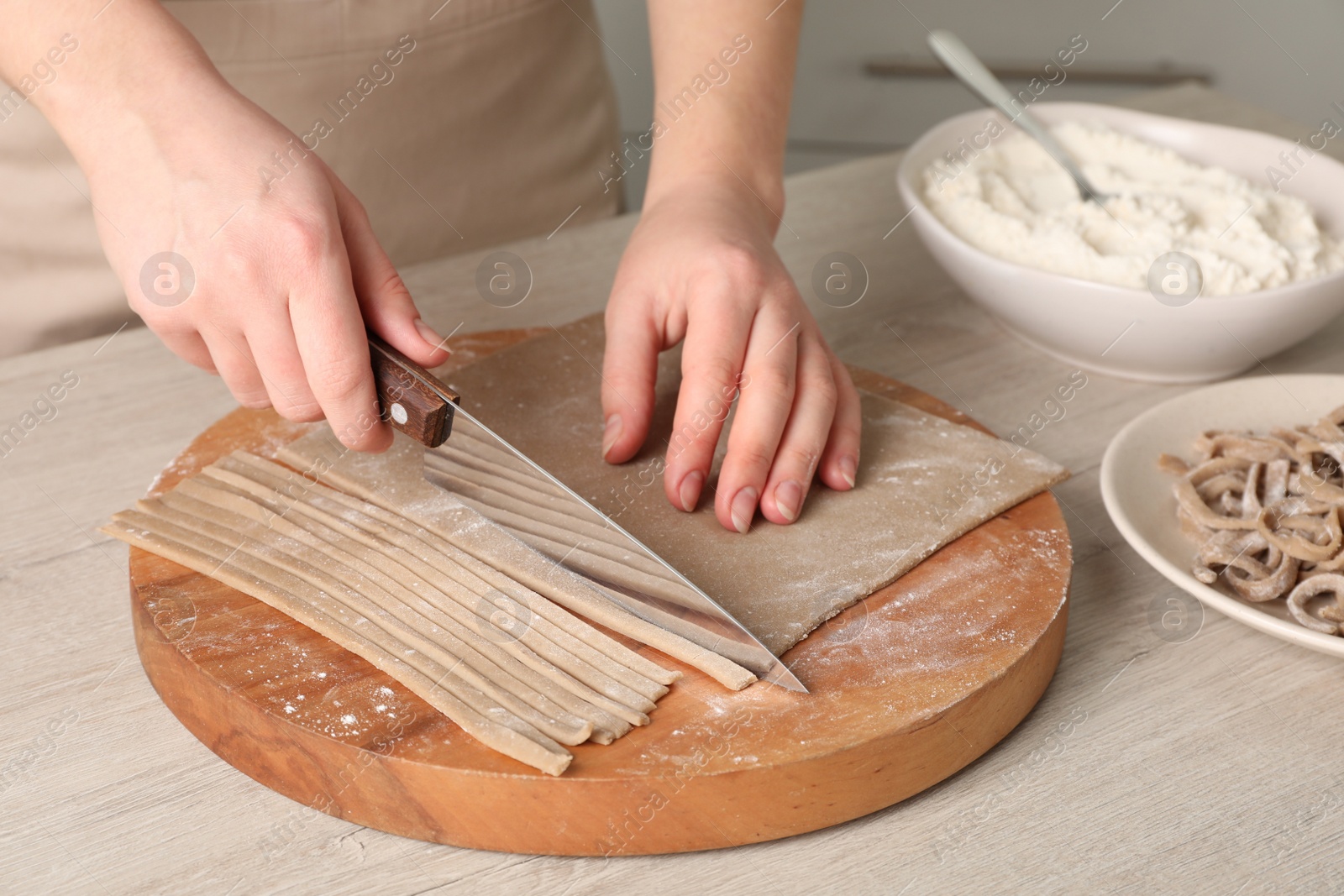 Photo of Woman making soba (buckwheat noodles) at wooden table, closeup