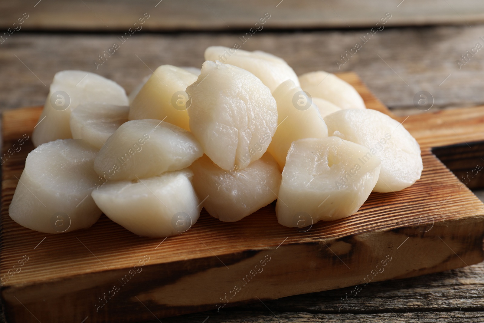 Photo of Fresh raw scallops on wooden table, closeup