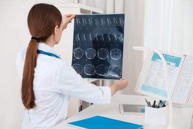 Orthopedist examining X-ray picture at desk in clinic