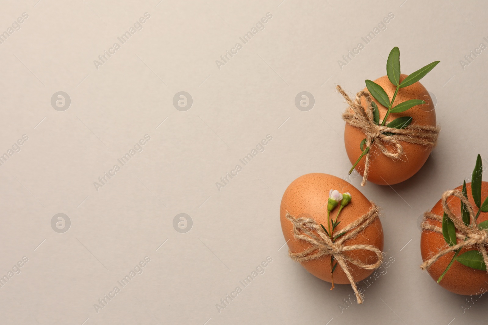 Photo of Festively decorated chicken eggs on light grey background, flat lay with space for text. Happy Easter