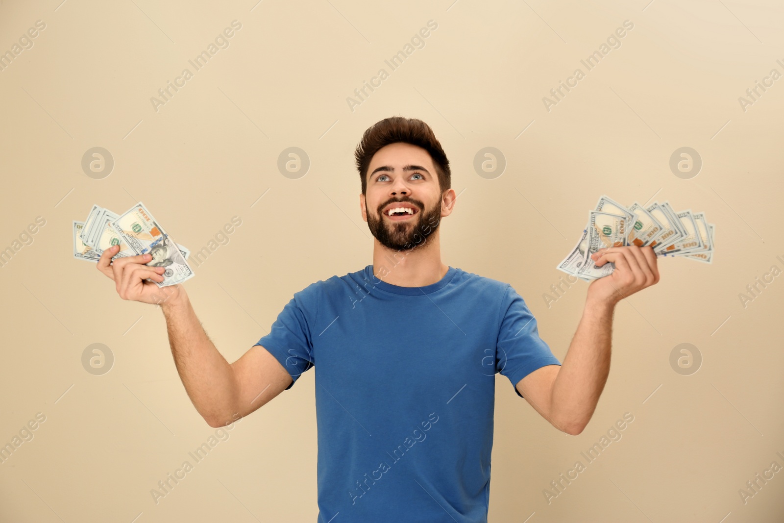 Photo of Portrait of happy young man with money on color background