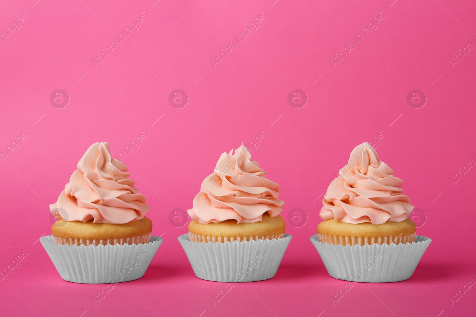 Photo of Tasty cupcakes with cream on pink background