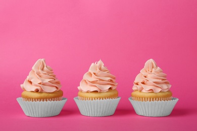 Tasty cupcakes with cream on pink background