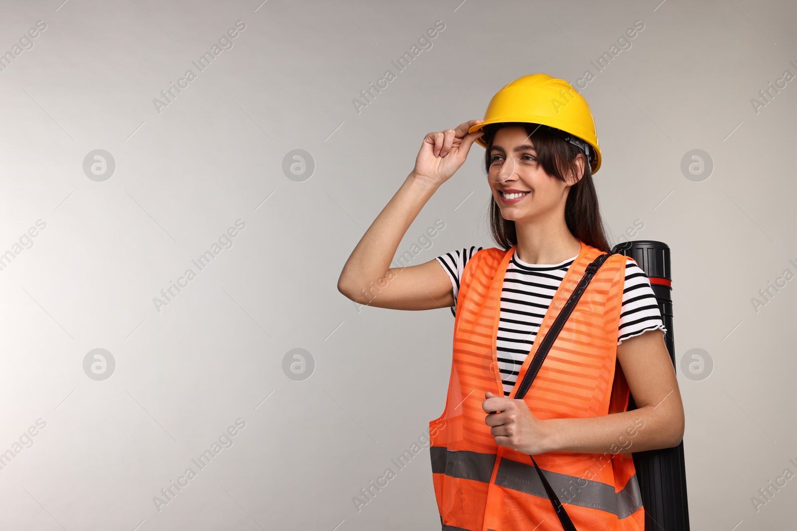 Photo of Architect in hard hat with tube on light grey background, space for text