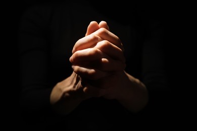 Photo of Religion. Christian woman praying on black background, closeup