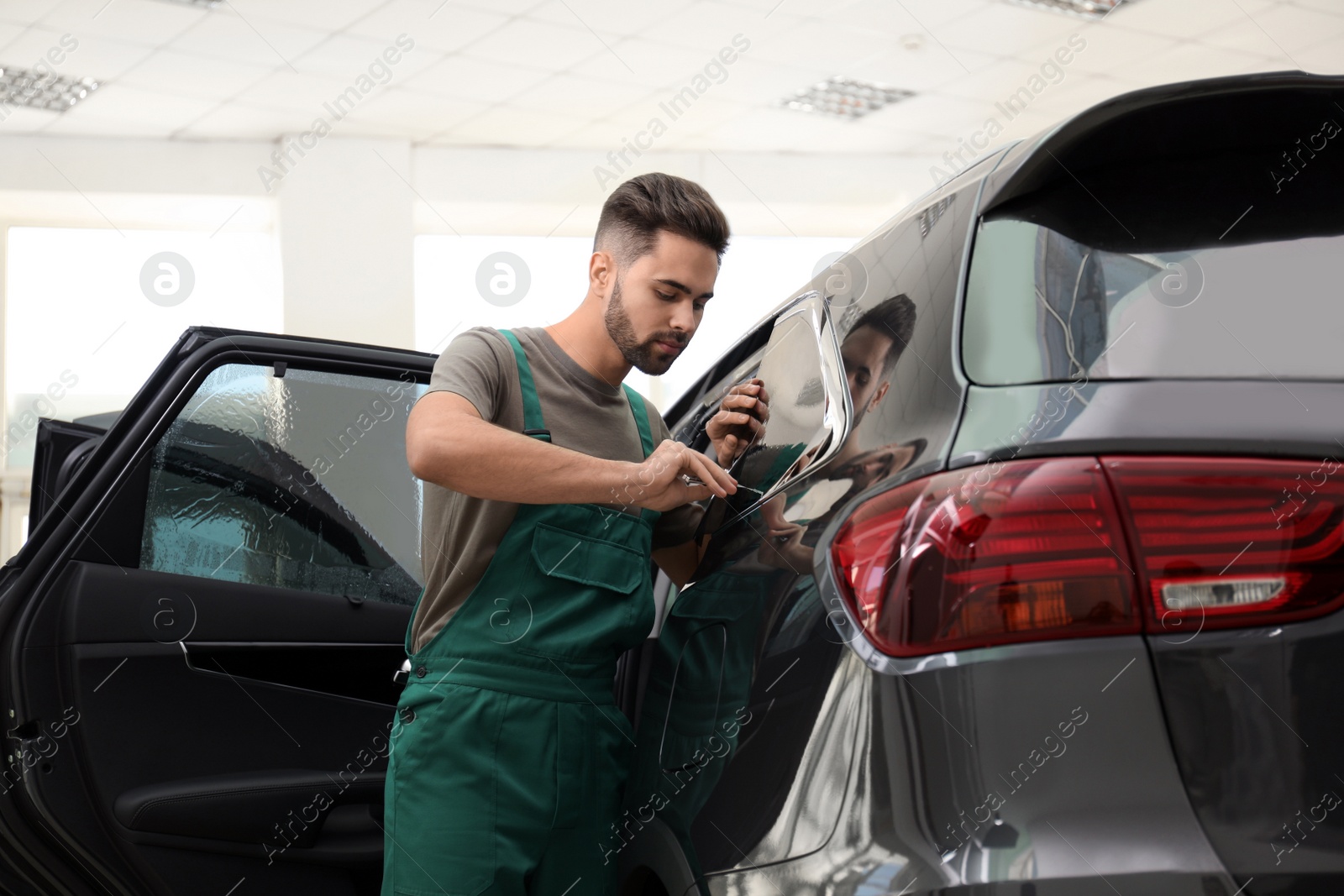 Photo of Worker tinting car window with foil in workshop