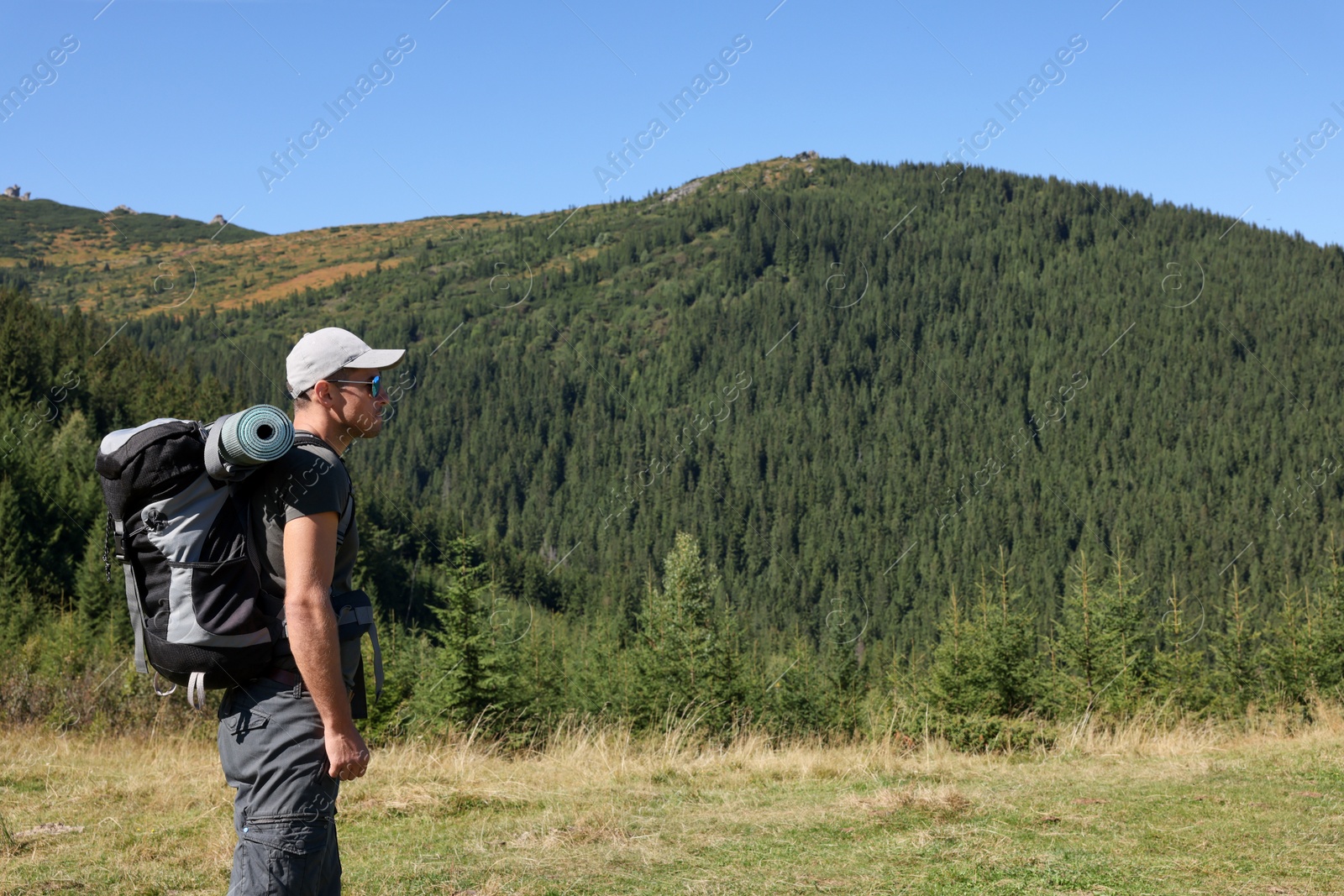 Photo of Man with backpack and sleeping mat in mountains. Space for text