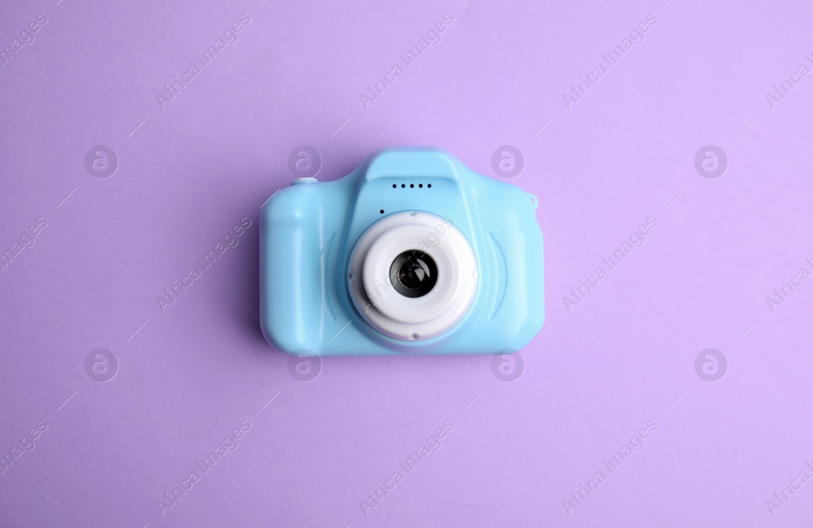 Photo of Light blue toy camera on violet background, top view. Future photographer