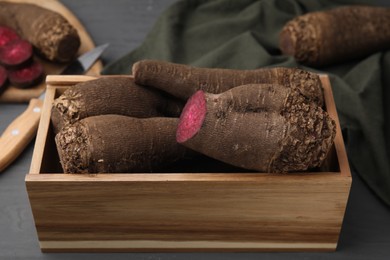 Whole and cut red beets in wooden crate on table, closeup