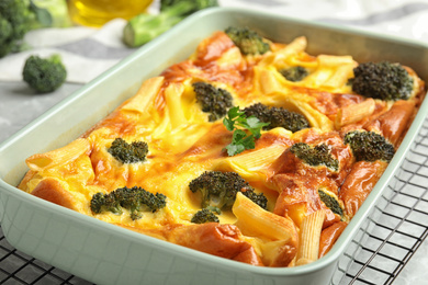 Photo of Tasty broccoli casserole in baking dish on cooling rack, closeup