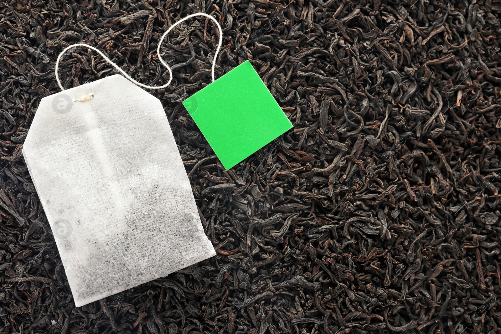 Photo of Tea bag on dry leaves, top view with space for text