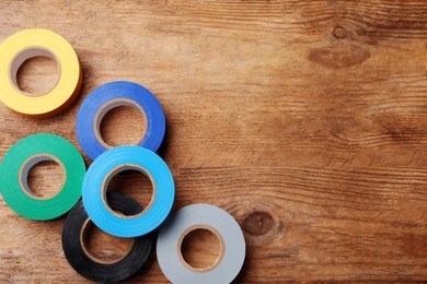 Photo of Colorful insulating tapes on wooden table, flat lay. Space for text