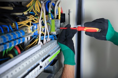 Photo of Electrician repairing fuse box with screwdriver, closeup