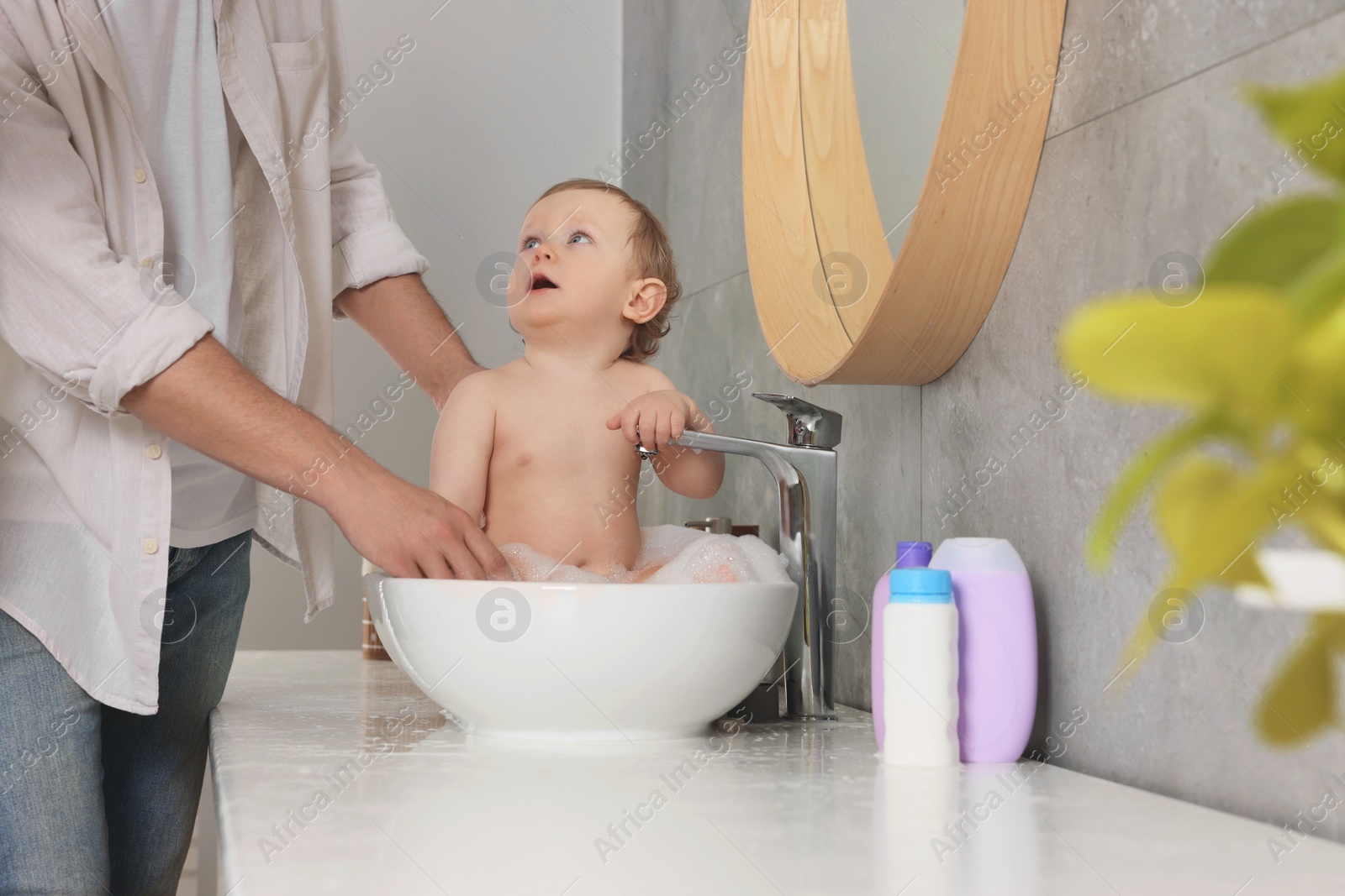 Photo of Father washing his little baby in sink at home