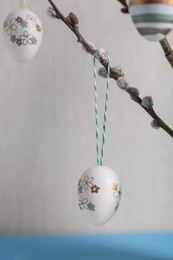 Photo of Beautiful willow branches with painted eggs on light blue table. Easter decor