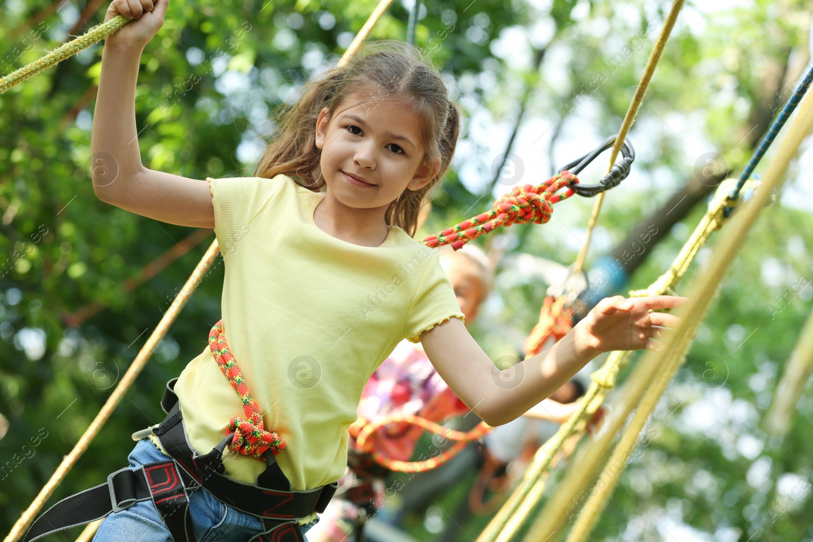 Photo of Little girl climbing in adventure park. Summer camp