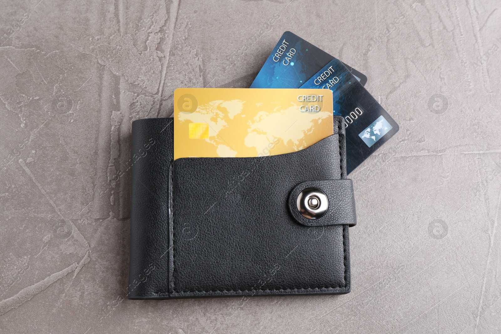 Photo of Leather wallet with credit cards on grey textured table, top view