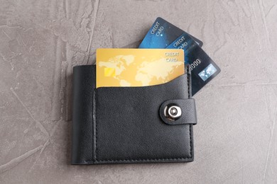 Leather wallet with credit cards on grey textured table, top view