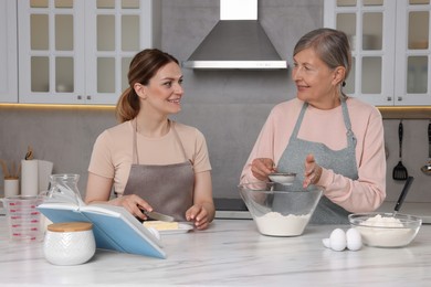Photo of Happy women cooking by recipe book in kitchen