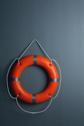 Photo of Orange lifebuoy on grey background. Rescue equipment