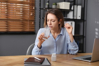 Photo of Woman holding glass of medicine for hangover in office