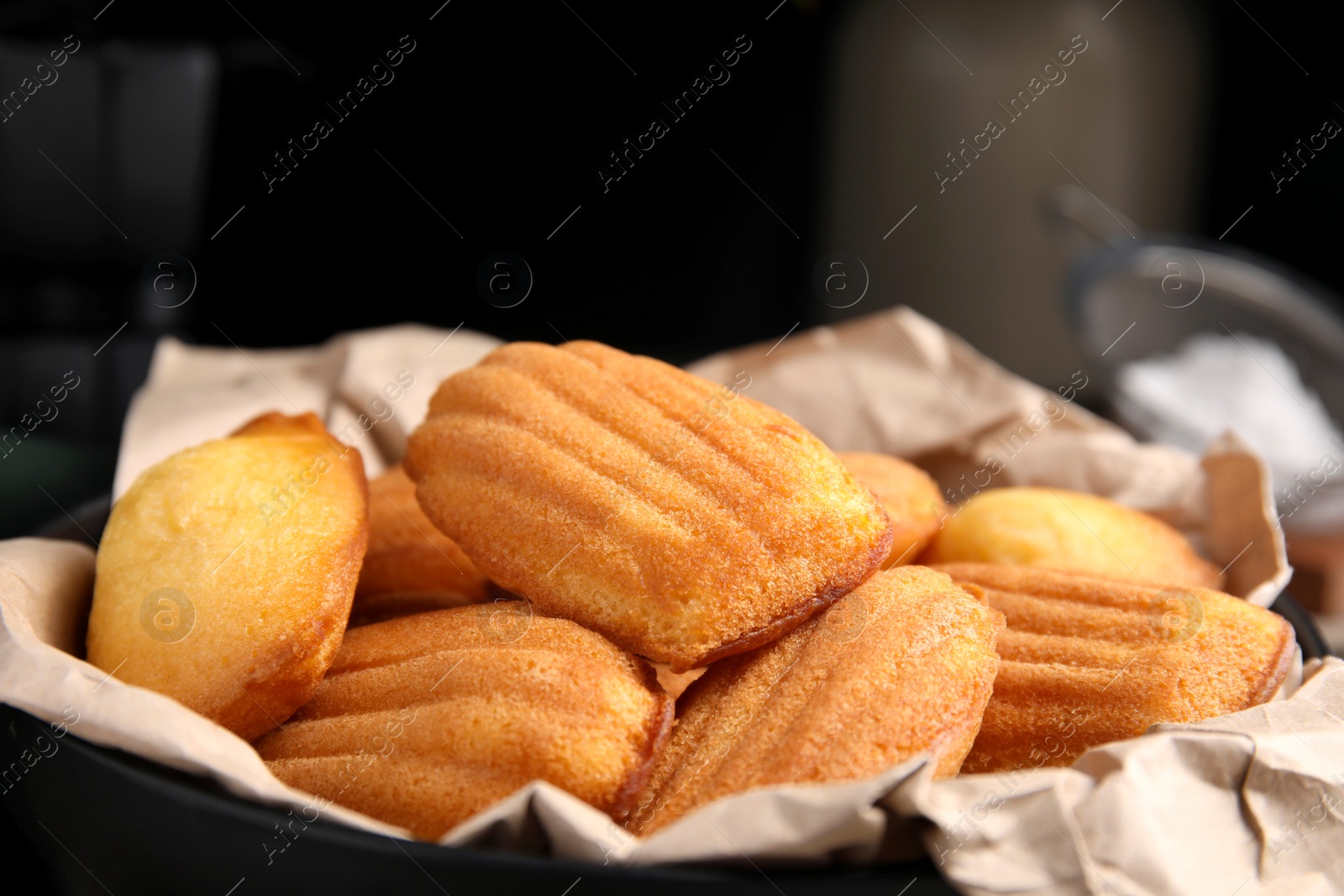 Photo of Delicious madeleine cakes in bowl, closeup view