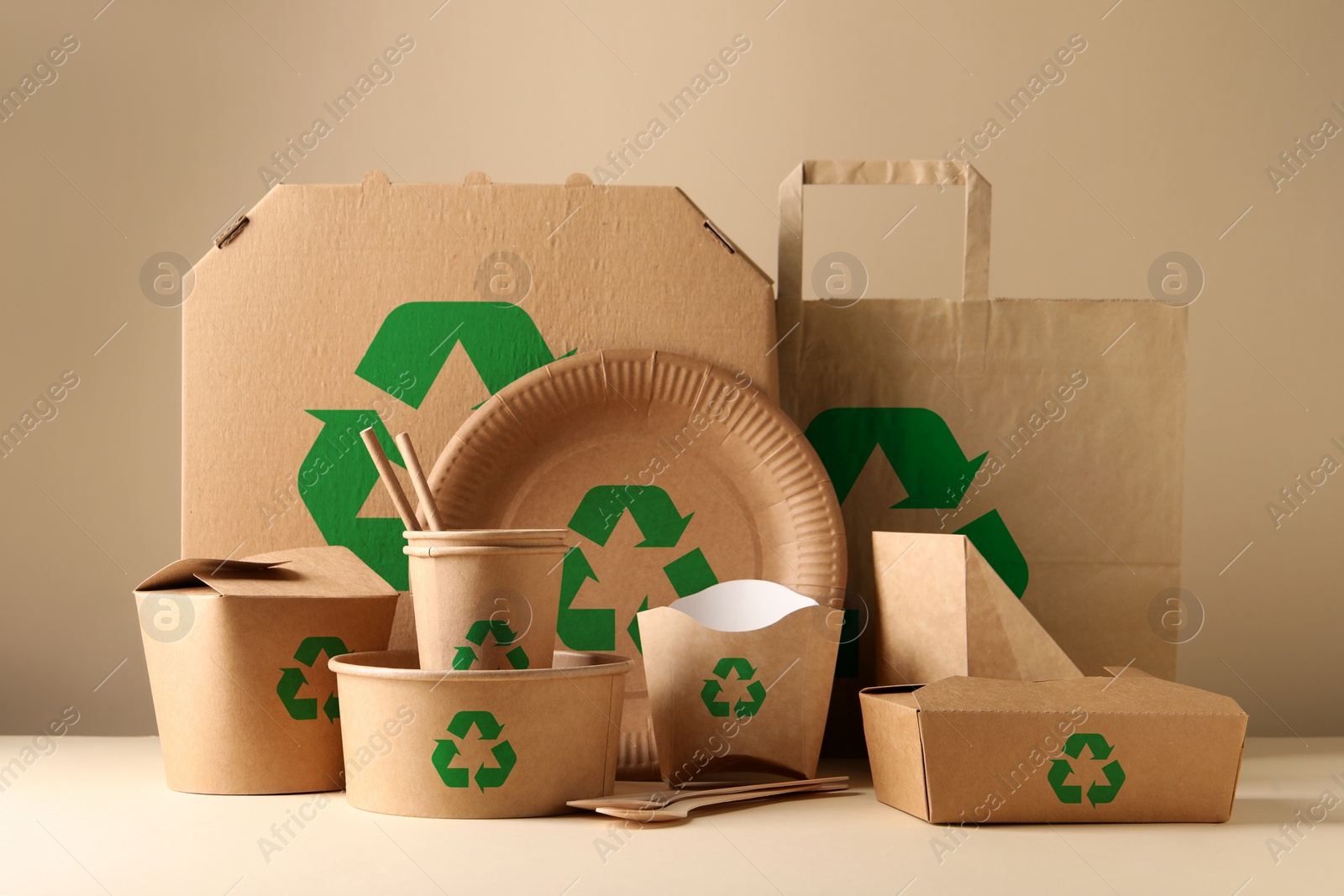 Image of Set of eco friendly food packaging with recycling symbols on table against beige background