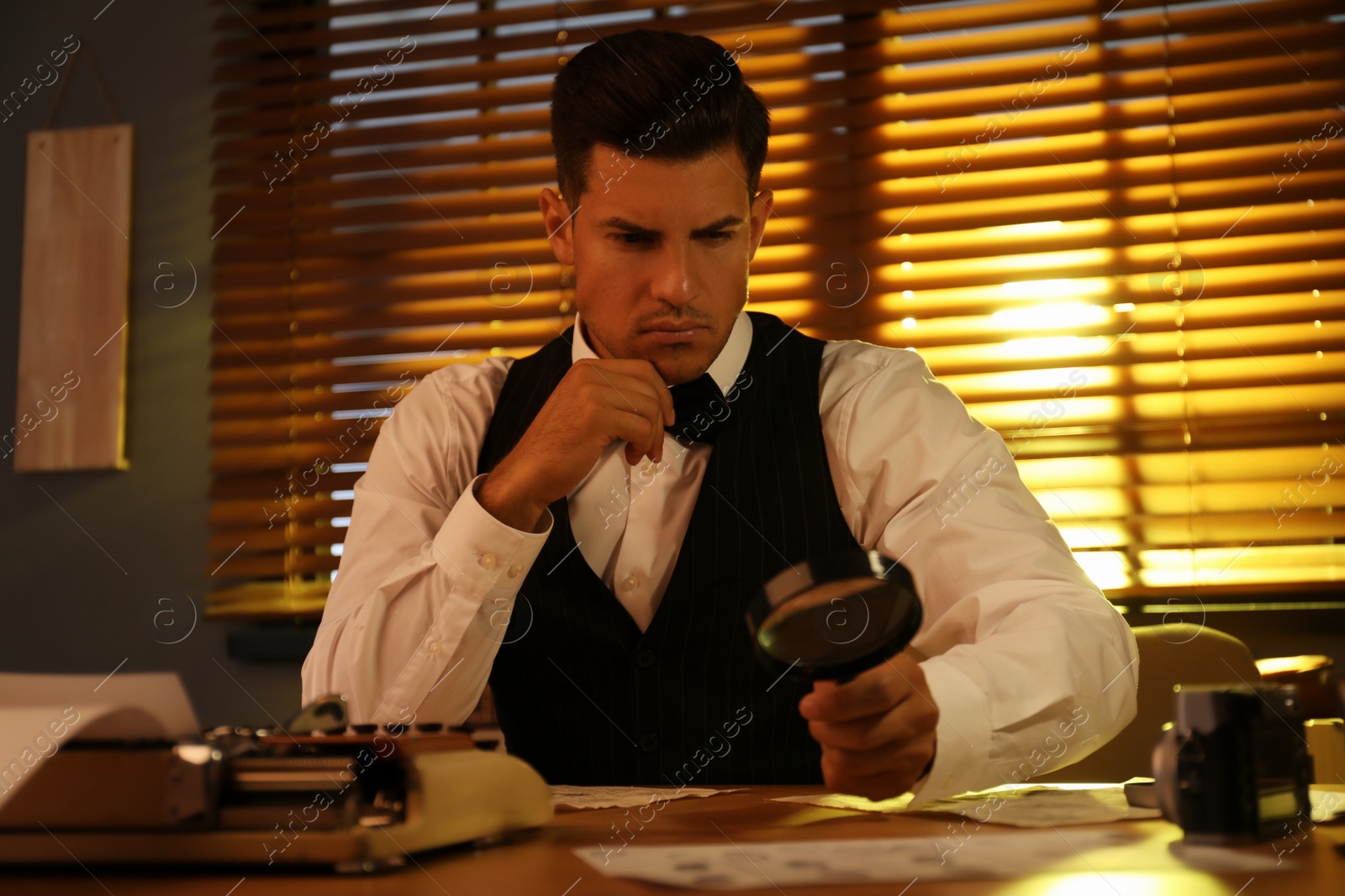 Photo of Old fashioned detective with magnifying glass working in office