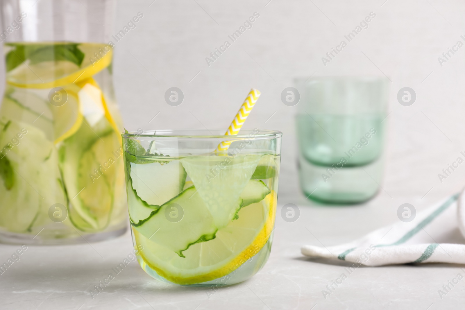 Photo of Refreshing water with cucumber, lemon and mint on white table