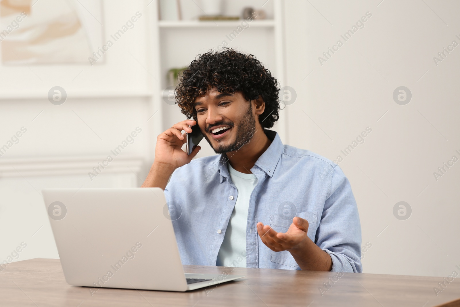 Photo of Handsome smiling man talking on smartphone in room