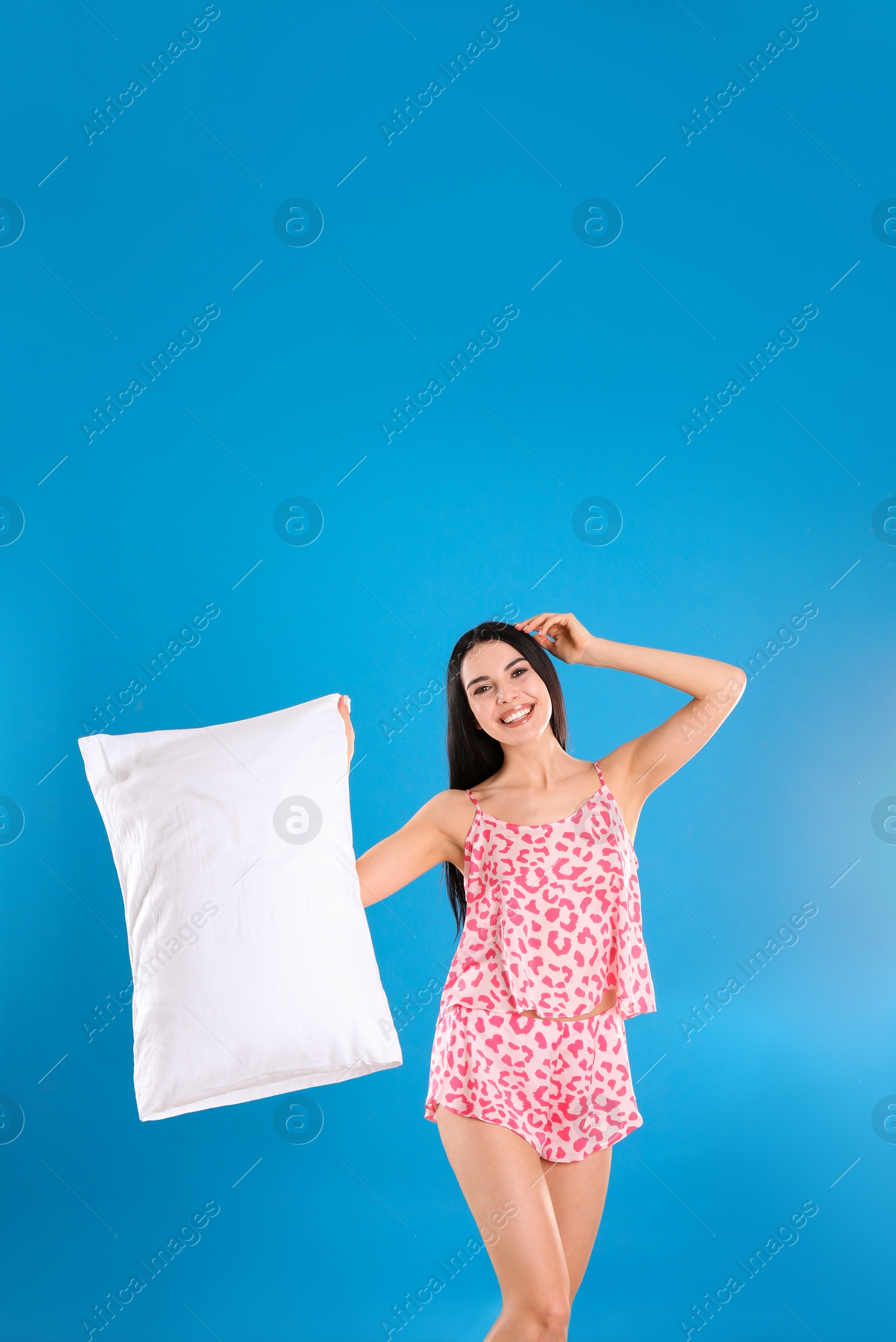 Photo of Young woman with pillow on blue background