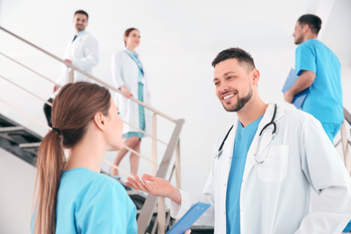 Male doctor talking to colleague on staircase in clinic