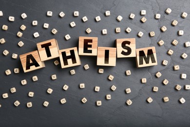 Word Atheism made of wooden cubes with letters on grey table, flat lay