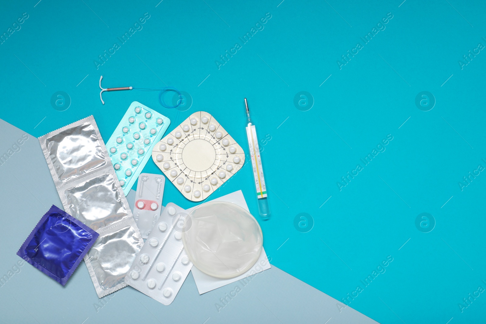 Photo of Contraceptive pills, condoms, intrauterine device and thermometer on color background, flat lay with space for text. Choice of birth control method