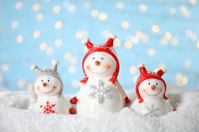 Photo of Decorative snowmen on artificial snow against blurred festive lights