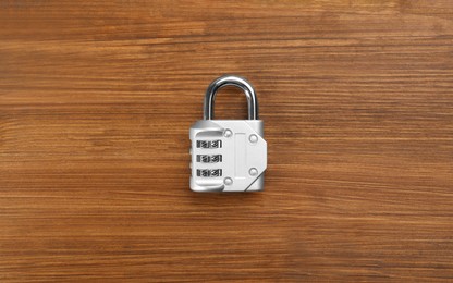 Modern combination lock on wooden table, top view