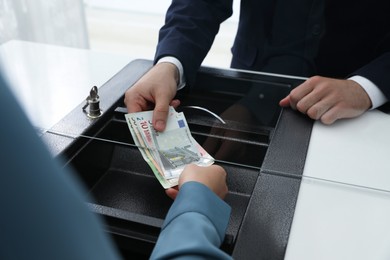 Photo of Woman giving money to cashier in bank, closeup. Currency exchange