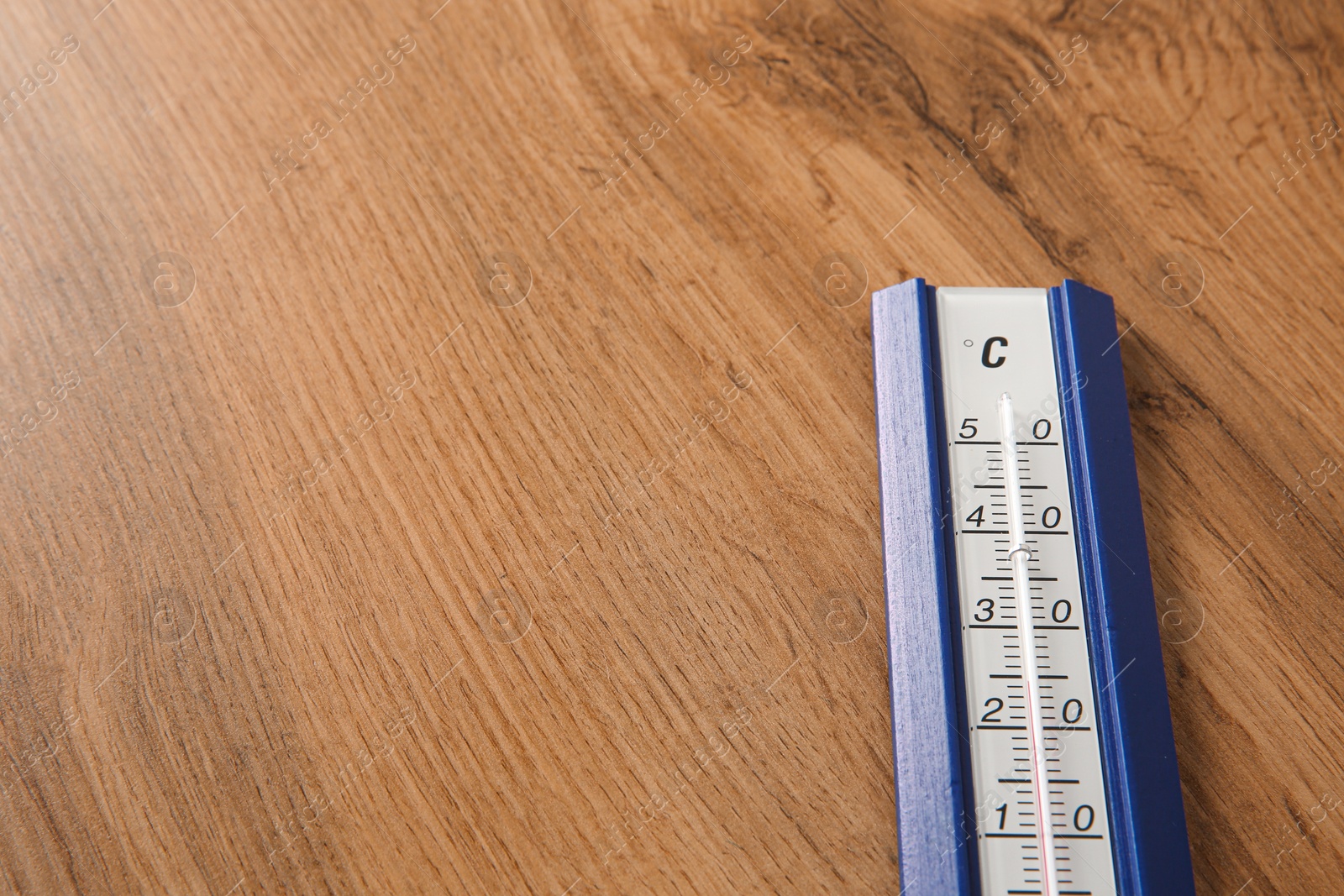 Photo of Weather thermometer on wooden table, closeup. Space for text