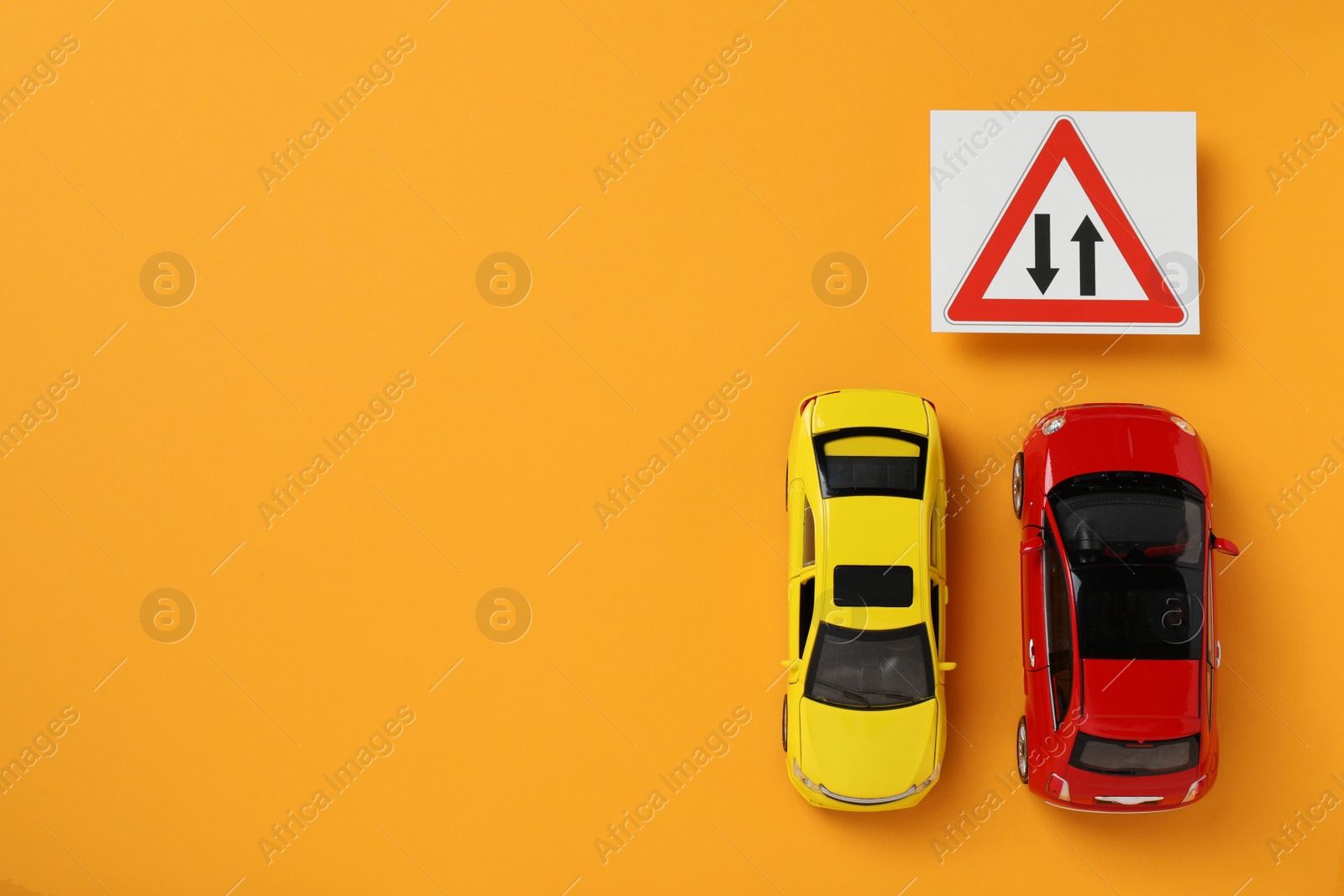Photo of Toy cars and road sign Two Way Direction on yellow background, flat lay. Space for text