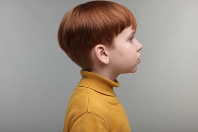 Photo of Hearing problem. Little boy on grey background