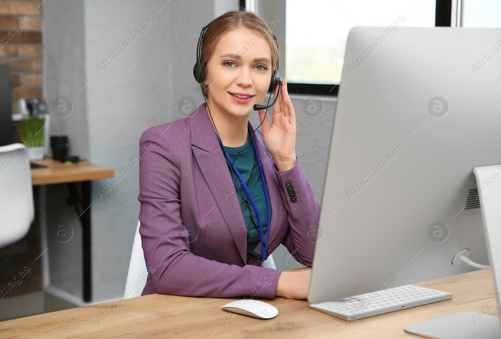 Photo of Technical support operator working with headset and computer at table in office