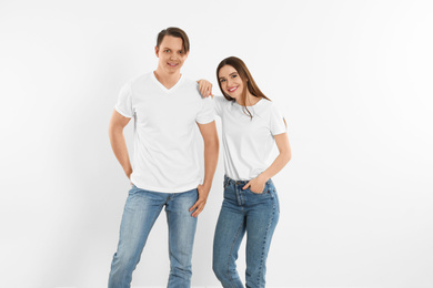 Young couple in stylish jeans near white wall