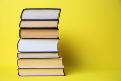 Photo of Collection of hardcover books on yellow background, space for text